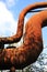 Landschaftspark Duisburg, Germany: Low angle view on isolated curved corroded pipeline against blue sky and trees