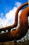 Landschaftspark Duisburg, Germany: Low angle view on isolated curved corroded pipeline against blue sky and trees