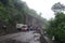 landslide blocking a road, with police and rescue vehicles parked nearby