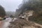 landslide blocking a road, with rescue vehicles on standby