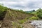 Landslide in the village. Rocks and ground are destroyed. Sunny weather. Plants die. Cataclysms. The texture of the stones.