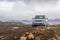 Langjokull Glacier SUV on muddy road standing between rocks in front of mountains