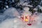 Lantern with a burning candle under a snow-covered Christmas tree in the courtyard of the house in the snowdrifts