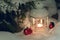 Lantern with a burning candle under a snow-covered Christmas tree in the courtyard of the house in the snowdrifts