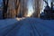 a lantern casting long shadows on a snow-covered road under the full moon