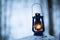 Lantern at dark in the forest at wintertime. Hiking, wilderness and peace concepts. Copy space. Blurred background.