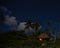 A lantern lights up the inside of a bungalow at night under the stars with palm trees surrounding it on an island in the South