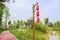 Lantern-shaped streetlamp by lakeside red path in sunny spring