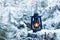 Lantern standing and glowing in the snow at evening. Vintage hand lantern a wooden stump in the woods during the winter season.