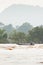 Laos fishermen on fishing boat in rapids of Mekong River. The Mekong River is going overflow. Tropical forest and mountains