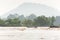 Laos fishermen on fishing boat in rapids of Mekong River. The Mekong River is going overflow. Tropical forest and mountains