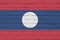 Laos flag depicted in paint colors on old brick wall. Textured banner on big brick wall masonry background