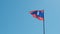 Laos national flag waving against a blue sky . slow motion .