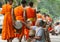 Laotian people making offerings to Buddhist monks during traditional alms giving ceremony in Luang Prabang city, Laos