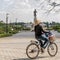 A Laotian woman rides a bicycle in the Chao Anouvong park with the large statue of King Chao Anouvong in the background in Vientia