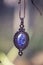 Lapis lazuli gemstone ornamental pendant on blury forest background