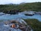 Lapland landscape with burning campfire and rapids of wild river Kamajakka, rock, birch trees and mountains at Rovvidievva sami