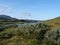 Lapland nature landscape with blue glacial river and Alesjaure STF Mountain cabin hut, birch tree forest, snow capped mountains