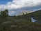 Lapland nature landscape with blue glacial river and Alesjaure STF Mountain cabin hut, birch tree forest, snow capped mountains