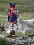 A Laplander in traditional dress feeding his reindeer in North Norway during the midnight sun.