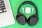 Laptop with big and small wireless headphones on green background