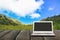 Laptop with blank screen on wooden table with forest in mountain