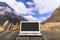 Laptop with blank screen on wooden table with forest in mountain