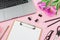 Laptop, clipboard, tulips flowers, glasses, pen and scissors on pink background. Flat lay. Top view. Freelancer office concept