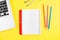 Laptop, colorful pensils, divider, and notepad planner on yellow background. Flat lay. Copy space. Workplace in the office