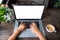 Laptop computer with hands of woman on wooden table