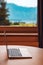 Laptop computer on living room desk by the window with beautiful scenic view of summer landscape