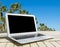 Laptop computer on wooden table. Front palm view. Tropical island background. Open blank laptop computer empty space. Front view