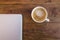 A laptop and a cup of coffee over a wood table