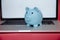 Laptop device and money box piggy in the pink room.