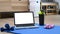 Laptop with empty screen, bottle of water and dumbbells on blue mat.