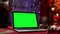 Laptop with green screen chroma key stands on red table next to Santa Claus, gifts and toys. Home room with Christmas