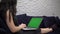 Laptop green screen mockup, woman using laptop on sofa at home