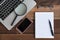 Laptop, Notebook, smartphone, spectacle and magnifying glass on wooden table