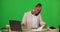 Laptop, phone call and black woman writing on green screen in studio isolated on a background. Cellphone, typing on
