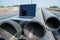 Laptop on pipes at a construction site. Reflection of a portrait of a builder in a helmet on the screen.