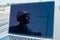 Laptop on pipes at a construction site. Reflection of a portrait of a builder in a helmet on the screen.