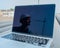 Laptop on pipes at a construction site. Reflection of a portrait of a builder in a helmet on the screen.