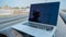 Laptop on pipes at a construction site. Reflection of a portrait of a builder in a helmet on the screen.