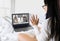 Laptop screen view over shoulder asian woman talking about work,sitting in bedroom make video call have distant communication