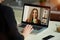 Laptop screen view over a woman`s shoulder. A girl works remotely on a computer