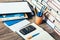 Laptop, smartphone, stack of books, notebook and pencils in orange plastic holder on wooden table, education concept background