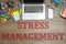 Laptop, stationery and text STRESS MANAGEMENT on table, flat lay