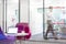 Laptop on table by pink chairs with defocused businessman walking in background