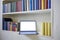 Laptop in very organized bookshelf in a white wall
