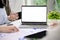 Laptop white screen mockup on a meeting table, businesspeople are in the meeting